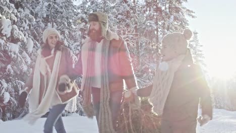 Familie-mit-Weihnachtsbaum-durch-Winterwald