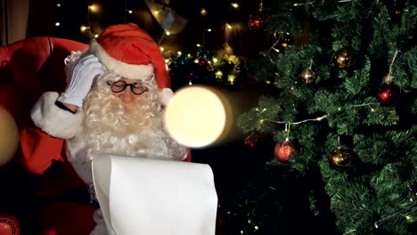 Santa-Close-up-cerca-decorado-árbol-de-Navidad-leyendo-lista-de-Navidad-desea.