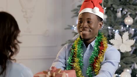 Man-in-Santa-hat-gives-a-gift-for-woman-on-Christmas-holiday