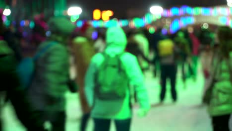 Deporte-de-invierno-de-concepto.-Multitud-en-la-ciudad-de-patinaje-la-noche-pista.-Gran-multitud-de-personas-alegres-que-se-divierten-patinando.-Nieve-que-cae.-Desenfoque-de-días-de-Navidad.-Deporte-y-buen-humor-concepción.-Familias-y-feliz-pareja-patinaje