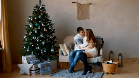 Atractiva-pareja-joven-sentada-y-besos-en-ambiente-romántico