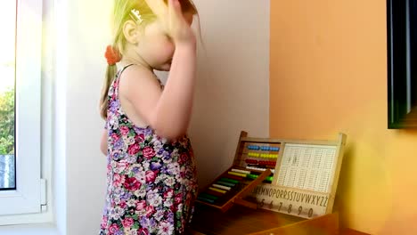 Sweet-little-girl-plays-with-abacus-and-writes-on-blackboard-with-chalk.-Preschool-concept,-childhood-concept.-Toy-abacus-with-Czech-alphabet.-Cute-girl-like-preschooler.-Bokeh-blur