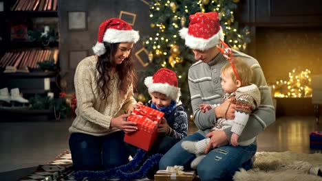 Family-opening-christmas-present-in-front-of-tree