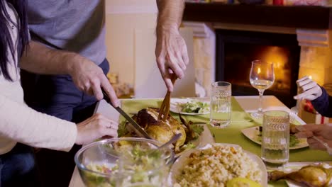 Padre-corta-pollo-frito-en-la-mesa-festiva-de-la-Navidad