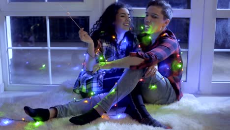 Beautiful-couple-decorated-with-christmas-garland-eats-marshmellows