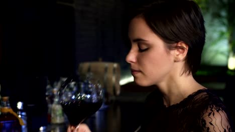 Close-up-of-a-gorgeous-brunette-enjoying-drinking-wine-at-the-bar-smiling-to-the-camera