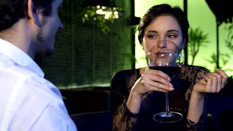 Wunderschöne-dunkelhaarige-Frau-Wein-zu-trinken,-während-das-Date-mit-ihrem-Freund