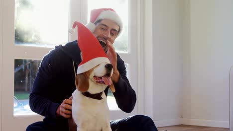 Sonriente-joven-poniendo-gorro-de-santa-en-su-mascota-perro-4K-4k