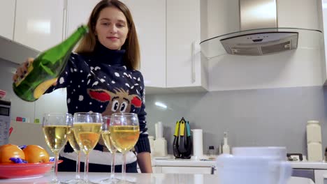 Niña-bonita-vierte-champagne-de-vasos-en-la-cocina-en-casa