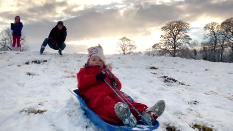 Toddler-girl-going-down-a-sledge-on-a-snowy-hill