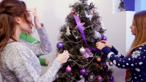 Three-girls-decorating-a-Christmas-tree-and-talking