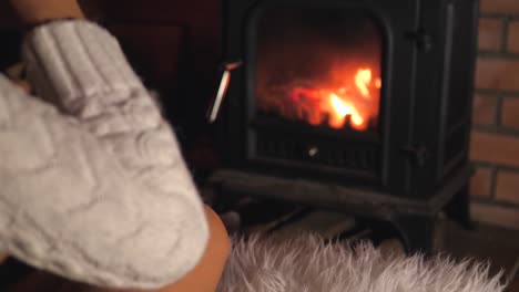 Mujer-sola-sentada-frente-a-la-chimenea-y-bebiendo-vino-de-una-copa