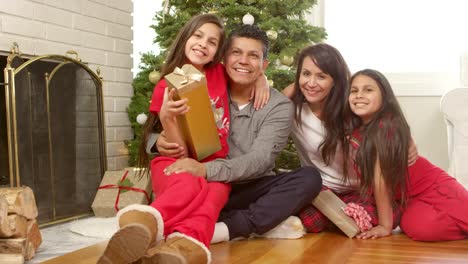 Familia-s\'encuentra-en-la-parte-delantera-de-un-árbol-de-Navidad-con-regalos