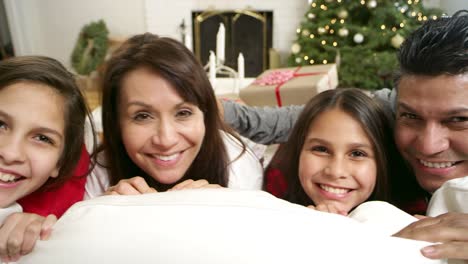 Pan-de-izquierda-a-derecha-de-una-familia-sonriendo-en-el-sofá-en-Navidad-por-la-mañana