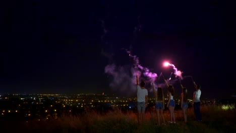 The-five-people-stand-with-firework-sticks-on-a-city-background.-night-time