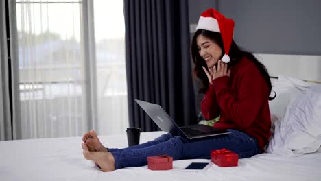happy-woman-using-laptop-computer-with-Christmas-gift-on-a-bed