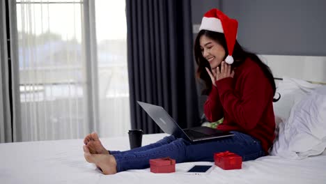 glückliche-Frau-mit-Laptop-Computer-mit-Weihnachtsgeschenk-auf-einem-Bett