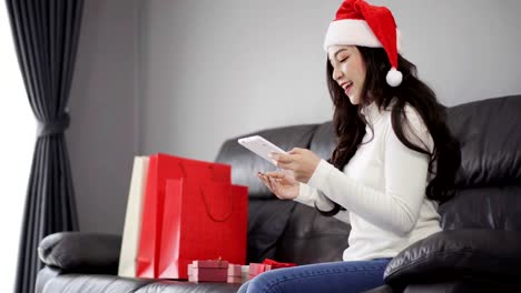 Frau-in-Santa-Hut-Online-shopping-für-Weihnachtsgeschenk-mit-digitalen-Tablet-PC-im-Wohnzimmer