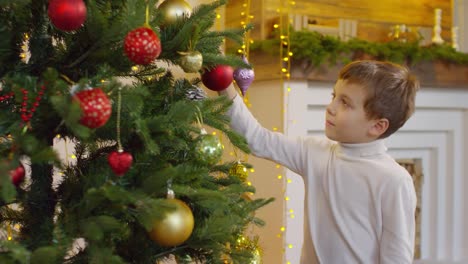 Kleiner-Junge-dekorieren-Weihnachtsbaum-zu-Hause