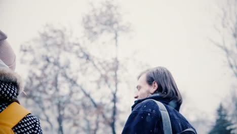 Close-up-back-view-of-two-happy-relaxed-Caucasian-friends-walking-together-and-smiling-outside-on-cold-snowy-winter-day.