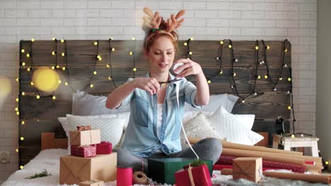 Glückliches-Mädchen-wickeln-die-Weihnachtsgeschenke-im-Bett