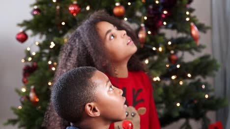 Kinder-Spiel-Scharade-mit-Weihnachtsbaum-im-Hintergrund-beobachten