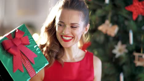 glückliche-junge-Hausfrau-mit-Weihnachtsgeschenk-Weihnachtsbaum