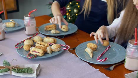 Hände-unter-Weihnachtsgebäck-und-Süßigkeiten-vom-Teller