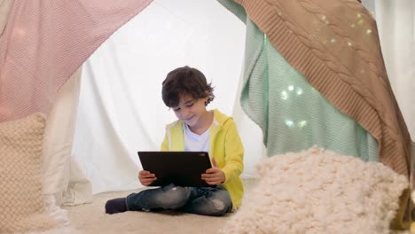 little-boy-with-tablet-pc-in-kids-tent-at-homea