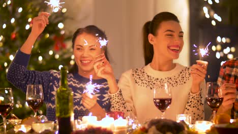 happy-friends-with-sparklers-having-christmas-dinner-at-home