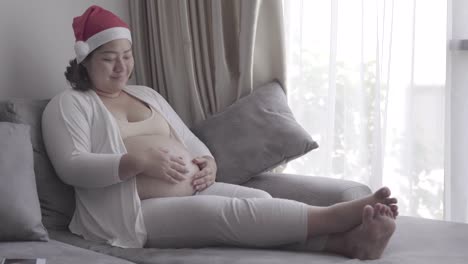 Mujer-asiática-en-suite-de-Santa-con-su-bebé-en-la-vida-de-embarazo,-sentado-en-el-sofá-o-sillón.