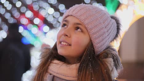 A-girl-looks-up-at-a-Christmas-tree-while-standing-in-the-square