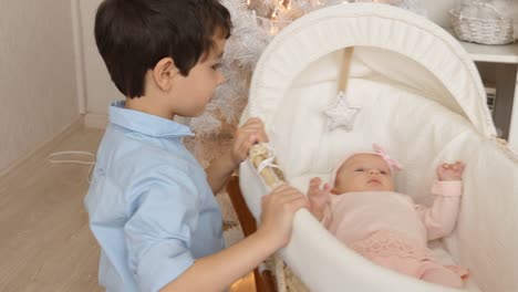 Little-brother-swings-at-bed-with-her-newborn-sister