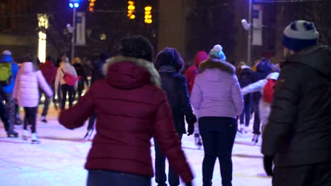 Concepto-de-invierno-y-la-nieve.-Multitud-en-la-pista-de-patinaje-de-la-ciudad-de-la-noche.-Nieve-que-cae.