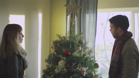 El-hombre-joven-pone-un-ornamento-de-la-estrella-en-la-tapa-del-árbol-de-Navidad