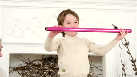 Little-boy-using-paper-roll-as-spy-glass-and-having-wrapping-paper-sword-fight-with-his-mom