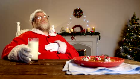 Santa-claus-relaxing-on-chair-and-having-sweet-food