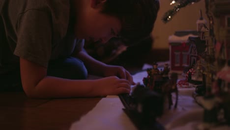 Little-boy-putting-together-train-tracks-in-front-of-the-christmas-tree