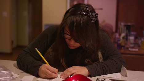 Una-chica-sentada-en-un-mostrador-de-cocina-escribiendo-en-un-trozo-de-papel