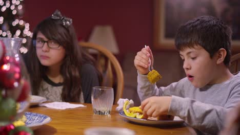 Siblings-eating-dinner-at-the-kitchen-table-at-Christmas-time