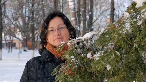 A-young-woman-in-a-Park-with-fir-on-the-street,-hands-touch-the-branches-of-trees,-examining-them.-Season-winter