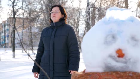 Junge-Frau-Gebäude-Schneemann-im-Park.-Im-winter