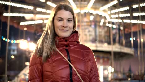 Young-beautiful-attractive-girl-having-fun-in-the-amusement-park.-Standing-near-merry-go-round