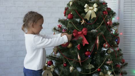 Niedliche-kleine-Mädchen-schmückt-den-Weihnachtsbaum.