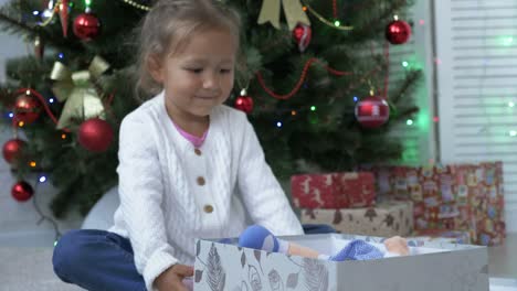 Nahaufnahme-der-niedliche-kleine-Mädchen-Weihnachtsgeschenk-zu-öffnen.