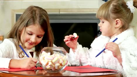 Kinder-einen-Stift-auf-ein-Blatt-Papier-zeichnen,-zwei-Mädchen-schreiben,-niedlichen-Kinder-sitzen-am-Kamin,-wo-das-Feuer-brennt