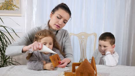 Junge-Mutter-mit-zwei-Kindern-macht-ein-Lebkuchenhaus