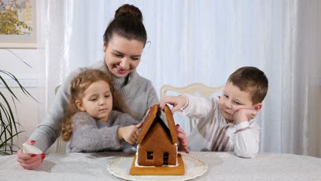 Beautiful-woman-with-little-children-makes-a-gingerbread-house