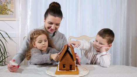 Schöne-Frau-mit-kleinen-Kindern-macht-ein-Lebkuchenhaus