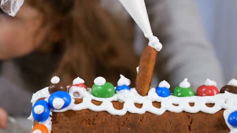 Decorating-a-gingerbread-house-with-colorful-candies-a-white-sweet-cream